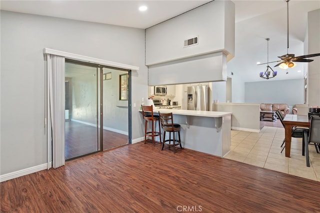 2837 Don Goodwin Dr, Riverside, CA 92507 - kitchen with appliances with stainless steel finishes, a high ceiling, a breakfast bar area, light wood-style floors, and a peninsula