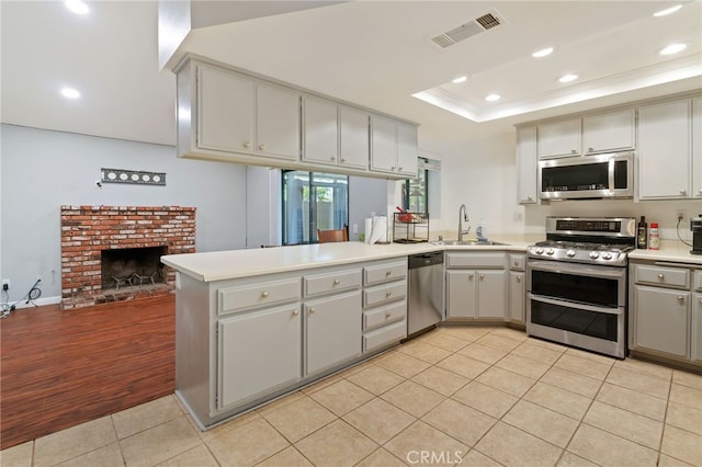2837 Don Goodwin Dr, Riverside, CA 92507 - kitchen featuring appliances with stainless steel finishes, light tile patterned floors, a peninsula, recessed lighting, and a fireplace