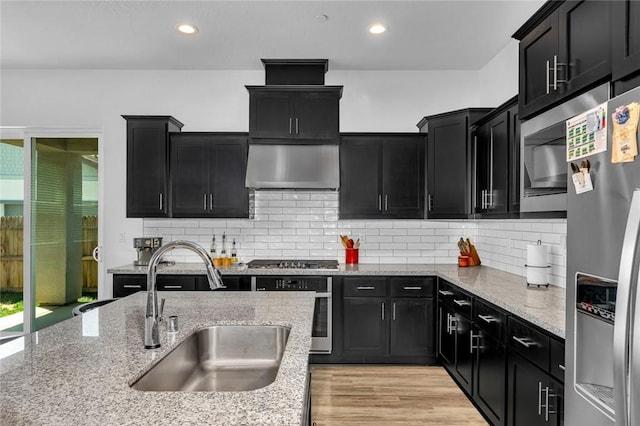 253 Peters Ln S, Madera, CA 93636 - kitchen with stainless steel appliances, dark cabinets, wall chimney exhaust hood, decorative backsplash, and recessed lighting