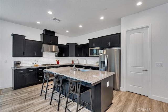 253 Peters Ln S, Madera, CA 93636 - kitchen featuring stainless steel appliances, under cabinet range hood, dark cabinetry, light stone countertops, and recessed lighting