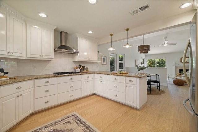 812 Collindale Ct, Chico, CA 95926 - kitchen featuring wall chimney range hood, light wood-type flooring, a peninsula, tasteful backsplash, and white cabinets