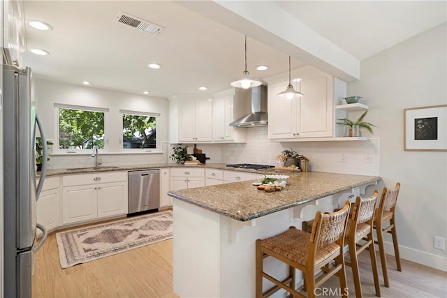812 Collindale Ct, Chico, CA 95926 - kitchen featuring stainless steel appliances, wall chimney range hood, a peninsula, light wood-style flooring, and recessed lighting