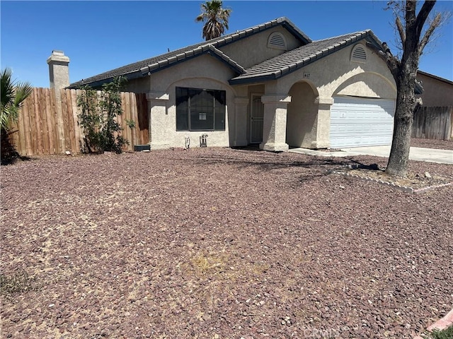 467 Stanford Dr, Barstow, CA 92311 - view of front of house with a garage, stucco siding, a tiled roof, and concrete driveway