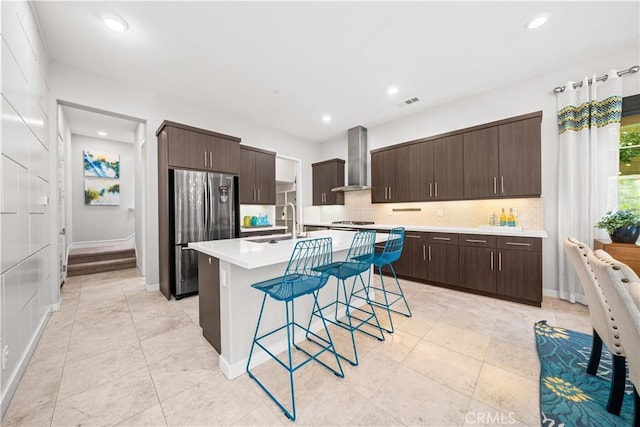 814 Beacon, Irvine, CA 92618 - kitchen with wall chimney range hood, appliances with stainless steel finishes, a breakfast bar, dark brown cabinetry, and tasteful backsplash