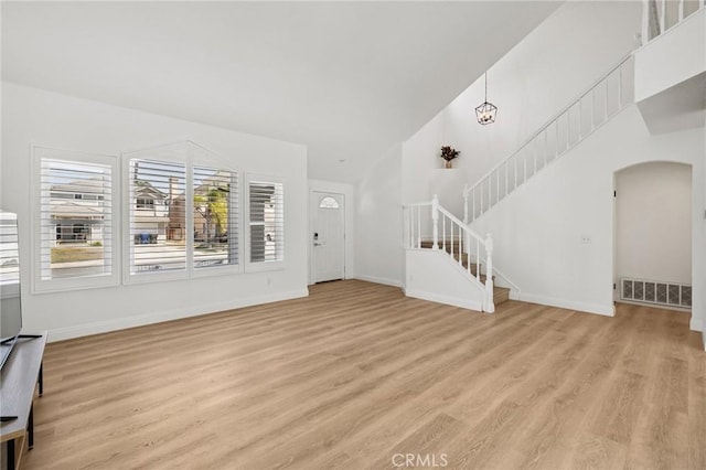 5731 Applecross Dr, Riverside, CA 92507 - unfurnished living room with arched walkways, light wood-type flooring, healthy amount of natural light, and stairway