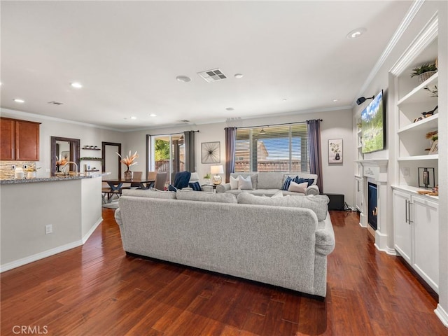 18387 Evening Primrose Ln, San Bernardino, CA 92407 - living room featuring ornamental molding, dark wood-style floors, recessed lighting, a glass covered fireplace, and built in shelves