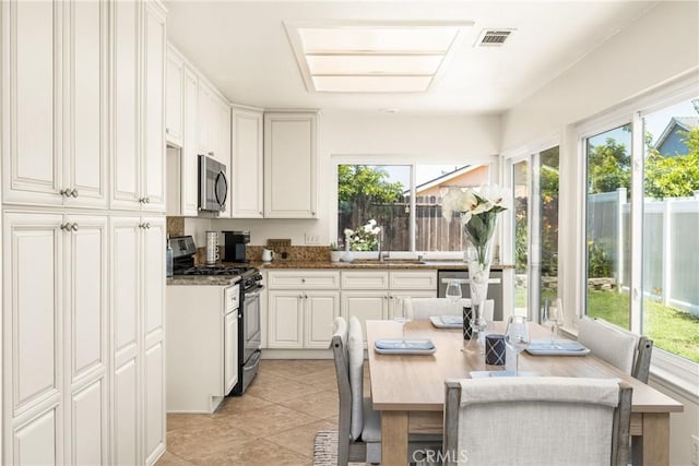 22811 Fortuna Ln, Mission Viejo, CA 92691 - kitchen featuring appliances with stainless steel finishes, white cabinetry, light tile patterned floors, and stone countertops