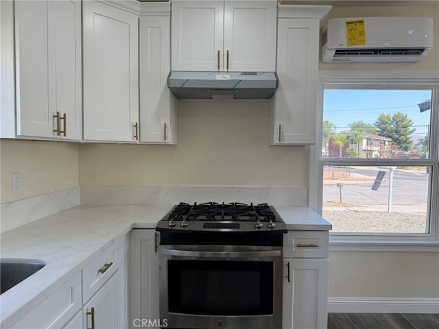 817 Orange Grove Ave, Colton, CA 92324 - kitchen featuring under cabinet range hood, a wall mounted air conditioner, stainless steel range with gas stovetop, and white cabinets