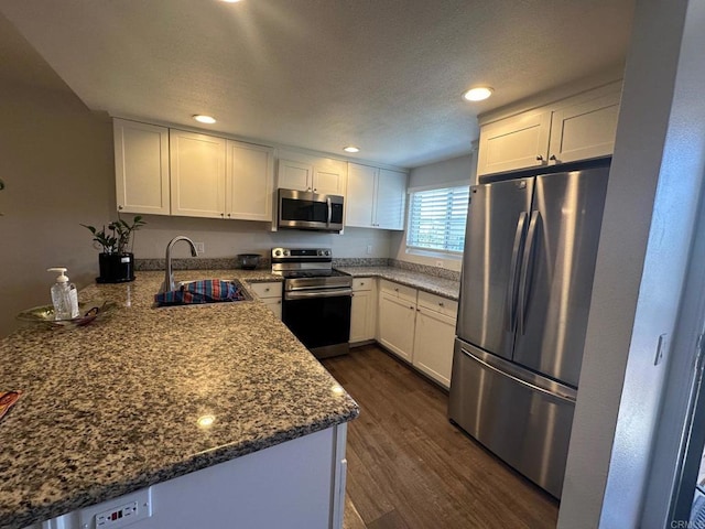 8733 Lake Murray Blvd Unit 6, San Diego, CA 92119 - kitchen featuring appliances with stainless steel finishes, dark wood finished floors, a peninsula, white cabinetry, and dark stone countertops