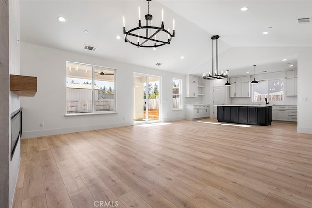 6779 Matell Rd, Paradise, CA 95969 - unfurnished living room with a chandelier, lofted ceiling, healthy amount of natural light, light wood finished floors, and recessed lighting