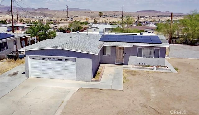 751 Yucca Ave, Barstow, CA 92311 - view of front facade featuring stucco siding, a mountain view, driveway, solar panels, and a garage