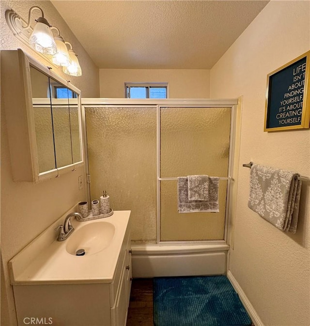 751 Yucca Ave, Barstow, CA 92311 - bathroom with vanity, shower / bath combination with glass door, a textured ceiling, and wood finished floors