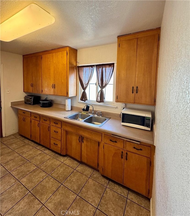 751 Yucca Ave, Barstow, CA 92311 - kitchen featuring white microwave, a textured wall, light countertops, a textured ceiling, and brown cabinetry