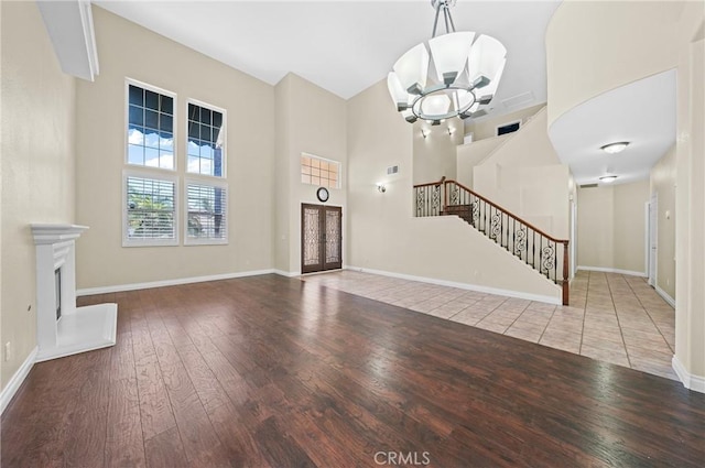 39647 Dartanian Pl, Murrieta, CA 92562 - unfurnished living room featuring a chandelier, a high ceiling, stairway, hardwood / wood-style floors, and a fireplace with raised hearth