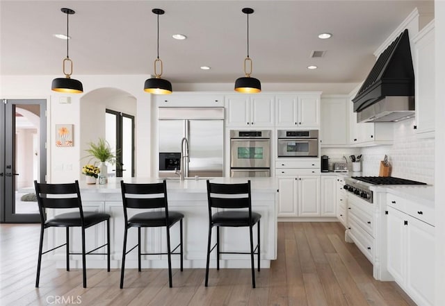 21 Via Nerisa, San Clemente, CA 92673 - kitchen featuring appliances with stainless steel finishes, custom range hood, arched walkways, light countertops, and white cabinets