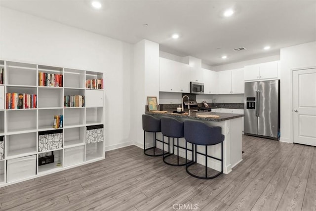 15958 Lasselle St Unit 2, Moreno Valley, CA 92551 - kitchen with appliances with stainless steel finishes, white cabinets, a peninsula, wood finished floors, and a kitchen bar