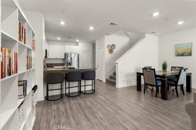 15958 Lasselle St Unit 2, Moreno Valley, CA 92551 - kitchen featuring stainless steel fridge, a peninsula, a breakfast bar area, light wood finished floors, and white cabinetry
