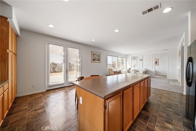 15453 La Casa Dr, Moreno Valley, CA 92555 - kitchen featuring a kitchen island, freestanding refrigerator, open floor plan, stone finish floors, and brown cabinets