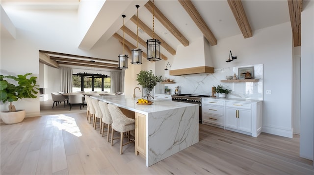 1901 Mariners Dr, Newport Beach, CA 92660 - kitchen with high end stainless steel range, light stone countertops, light wood-style flooring, a breakfast bar area, and decorative backsplash