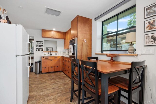 860 Nardo Rd, Encinitas, CA 92024 - kitchen featuring freestanding refrigerator, light countertops, wood finished floors, brown cabinets, and stainless steel oven