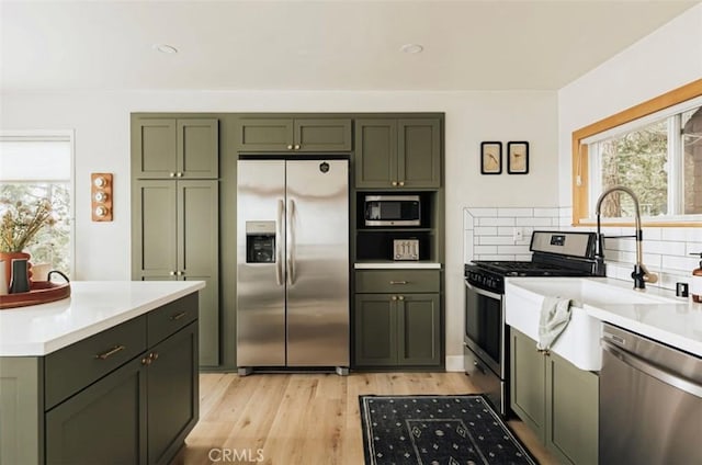 521 Sunderland Ct, Lake Arrowhead, CA 92352 - kitchen featuring stainless steel appliances, green cabinets, decorative backsplash, and light countertops