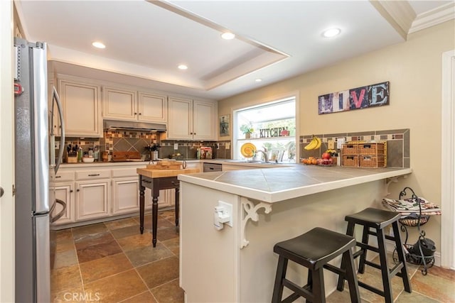 31032 Via Estenaga, San Juan Capistrano, CA 92675 - kitchen with freestanding refrigerator, a kitchen bar, a peninsula, tasteful backsplash, and recessed lighting
