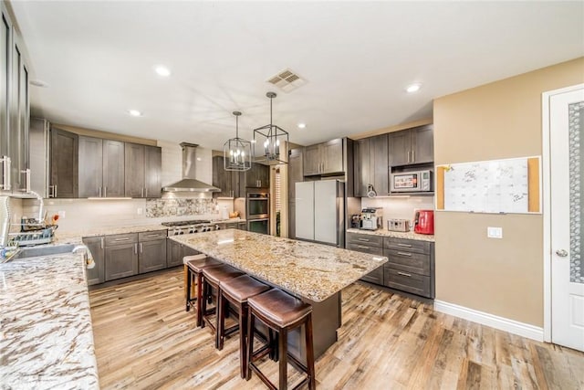 29155 Celestial Dr, Menifee, CA 92584 - kitchen featuring wall chimney exhaust hood, appliances with stainless steel finishes, light wood finished floors, light stone counters, and recessed lighting