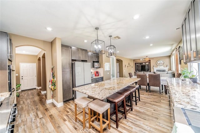 29155 Celestial Dr, Menifee, CA 92584 - kitchen featuring arched walkways, light wood-style flooring, ceiling fan, recessed lighting, and a kitchen breakfast bar