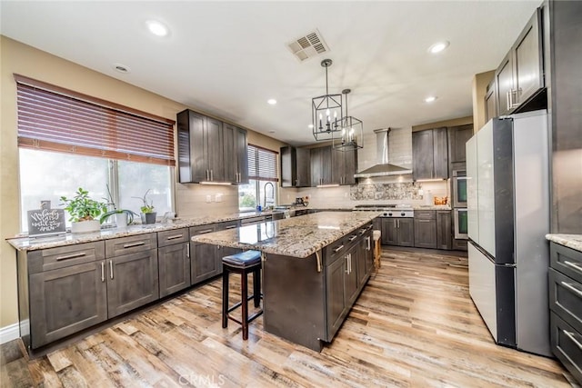29155 Celestial Dr, Menifee, CA 92584 - kitchen featuring freestanding refrigerator, wall chimney exhaust hood, light wood-type flooring, a kitchen island, and recessed lighting
