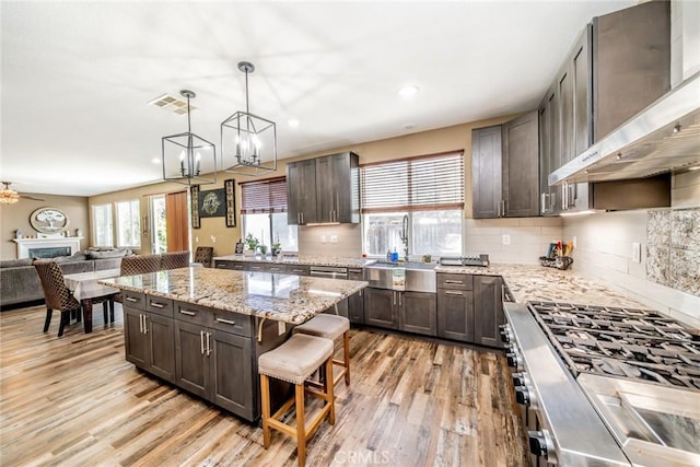 29155 Celestial Dr, Menifee, CA 92584 - kitchen with wall chimney range hood, range, light wood finished floors, open floor plan, and decorative backsplash