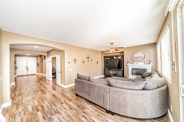 29155 Celestial Dr, Menifee, CA 92584 - living area featuring arched walkways, a ceiling fan, light wood-style flooring, and a glass covered fireplace