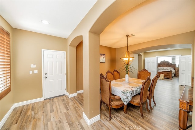 29155 Celestial Dr, Menifee, CA 92584 - dining space featuring arched walkways, light wood-type flooring, and a chandelier