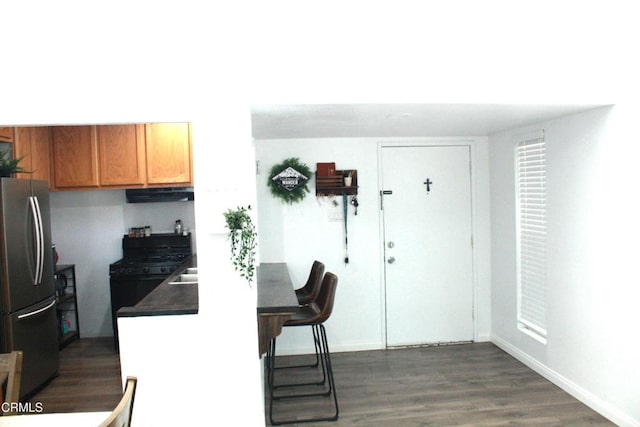 5246 Longfellow Way, Oxnard, CA 93033 - kitchen featuring freestanding refrigerator, under cabinet range hood, black gas stove, dark wood-style flooring, and dark countertops