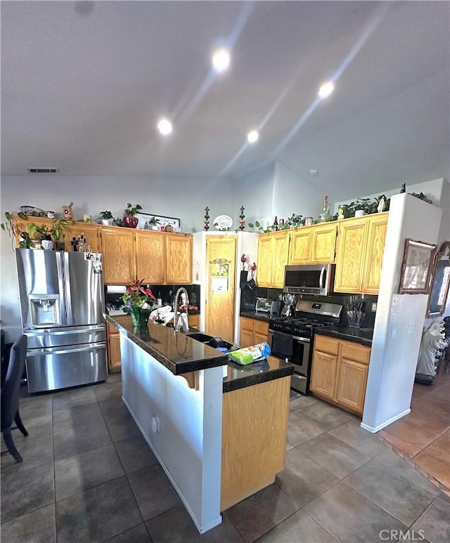 12649 Mesa Linda Ave, Victorville, CA 92392 - kitchen featuring appliances with stainless steel finishes, vaulted ceiling, dark countertops, a kitchen island with sink, and dark tile patterned floors