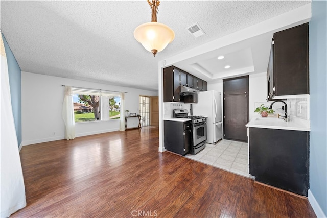 1456 Countrywood Ave Unit 14, Hacienda Heights, CA 91745 - kitchen featuring stainless steel range with gas cooktop, light countertops, freestanding refrigerator, light wood-type flooring, and a textured ceiling
