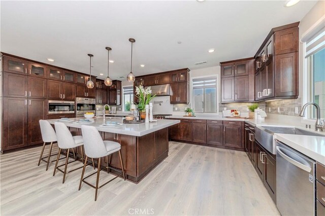 195 Stellar, Irvine, CA 92618 - kitchen with appliances with stainless steel finishes, under cabinet range hood, healthy amount of natural light, light wood-type flooring, and recessed lighting
