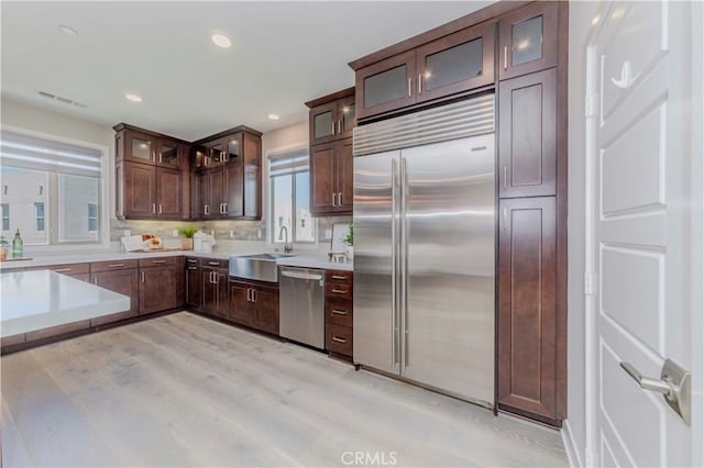 195 Stellar, Irvine, CA 92618 - kitchen featuring appliances with stainless steel finishes, dark brown cabinets, light countertops, decorative backsplash, and light wood-type flooring
