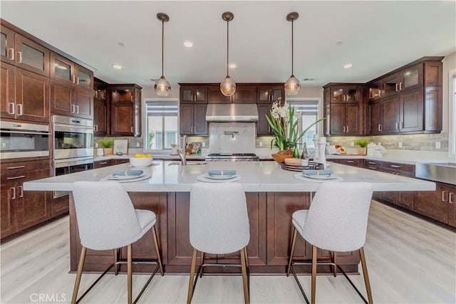 195 Stellar, Irvine, CA 92618 - kitchen with under cabinet range hood, light countertops, double oven, tasteful backsplash, and light wood-style flooring