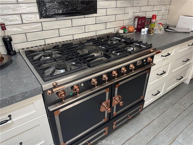 777 Oak Knoll St, Brea, CA 92821 - kitchen view of double oven range, decorative backsplash, white cabinets, dark countertops, and wood finished floors