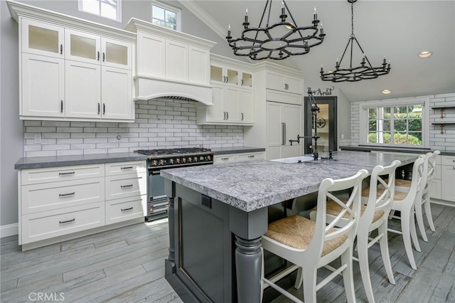 777 Oak Knoll St, Brea, CA 92821 - kitchen with stainless steel stove, a chandelier, decorative backsplash, premium range hood, and light wood-type flooring