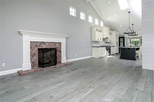 777 Oak Knoll St, Brea, CA 92821 - unfurnished living room featuring light wood-style floors, a fireplace, high vaulted ceiling, a chandelier, and beam ceiling