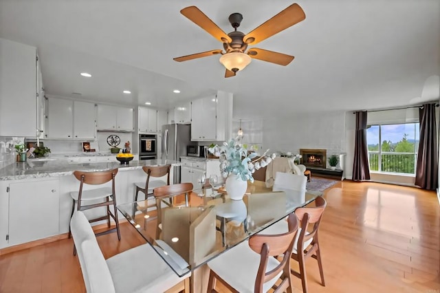 10160 Vista De La Cruz Ln, Mesa, CA 91941 - dining space featuring light wood-style flooring, recessed lighting, ceiling fan, and a warm lit fireplace