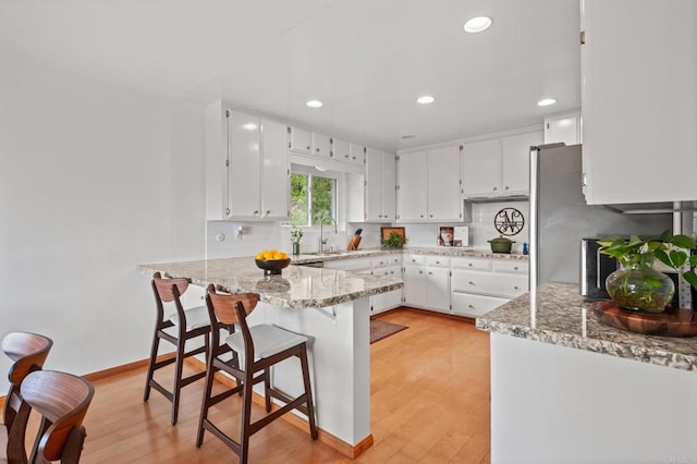 10160 Vista De La Cruz Ln, Mesa, CA 91941 - kitchen featuring light wood finished floors, white cabinetry, a peninsula, light stone countertops, and a breakfast bar area