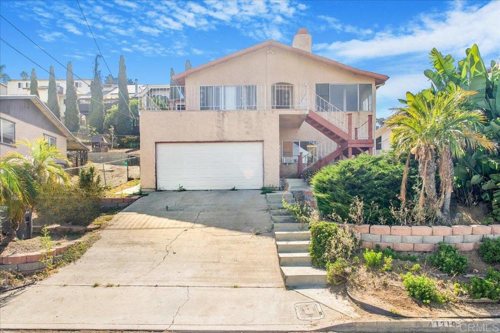 1319 Grand Ave, Spring Valley, CA 91977 - view of front facade with stairs, concrete driveway, stucco siding, a garage, and a chimney