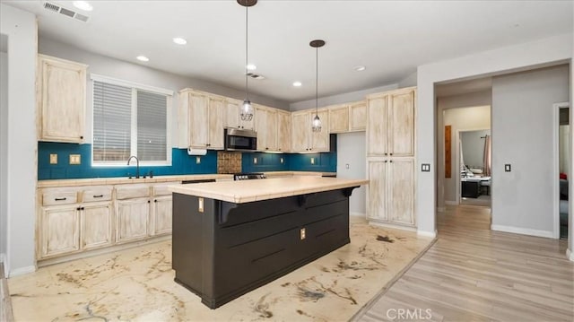 13849 Jackson St, Oak Hills, CA 92344 - kitchen featuring stainless steel microwave, light brown cabinetry, recessed lighting, backsplash, and a center island