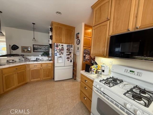 384 Papst Ave, Orland, CA 95963 - kitchen featuring white appliances, tile counters, light tile patterned flooring, a peninsula, and recessed lighting