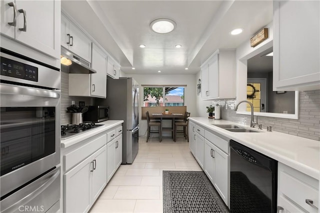 2816 E Alden Pl, Anaheim, CA 92806 - kitchen featuring appliances with stainless steel finishes, a warming drawer, under cabinet range hood, decorative backsplash, and light countertops