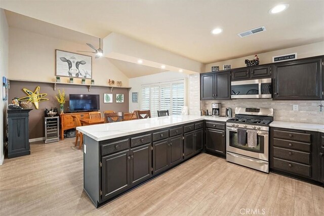 26309 Emerald Dove Dr, Valencia, CA 91355 - kitchen featuring stainless steel appliances, a peninsula, light wood-type flooring, decorative backsplash, and beverage cooler