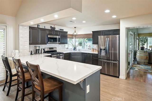 26309 Emerald Dove Dr, Valencia, CA 91355 - kitchen with appliances with stainless steel finishes, a peninsula, recessed lighting, light wood finished floors, and backsplash