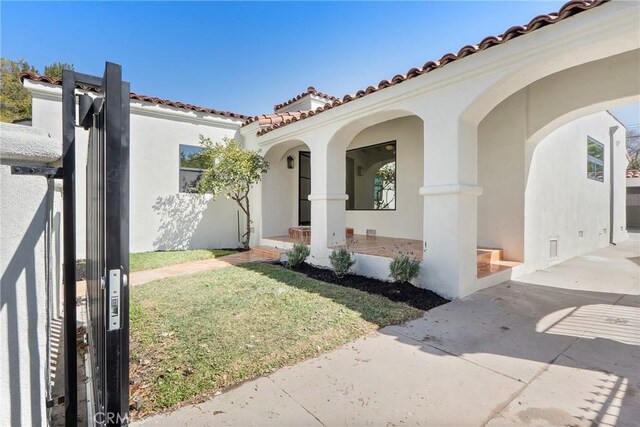 3924 Dublin Ave, Los Angeles, CA 90008 - doorway to property with stucco siding, a tiled roof, a porch, and a lawn